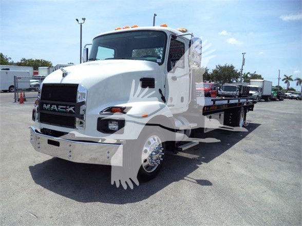 Mack MD6 tow truck front-left view with white cab and flatbed.