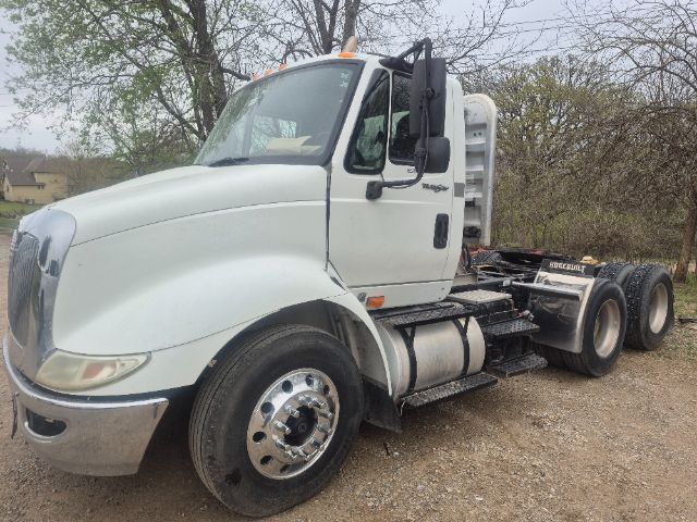 Volvo/International conventional daycab truck cab with front grille, dual rear axles, and fuel tanks visible.