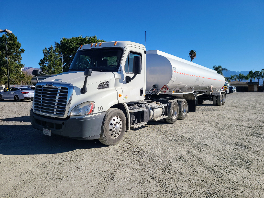 Beall semi truck and tanker trailer with white cab and cylindrical tanker, showing front grille, headlights, and tandem rear axles.