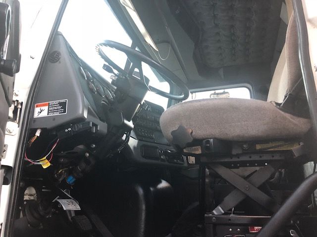 Cab interior of a 2012 Western Star grapple truck showing steering wheel, driver seat, and dashboard controls.