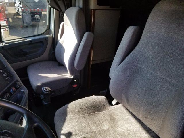 Truck cabin interior with two grey fabric seats, steering wheel on left, window, and dashboard visible.
