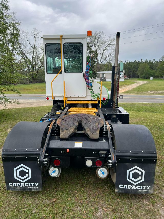 Capcity TJ 5000 yard truck chassis with white cab, dual rear fenders, and exposed hydraulic hoses. View from rear showing black mud flaps with Capacity logo.