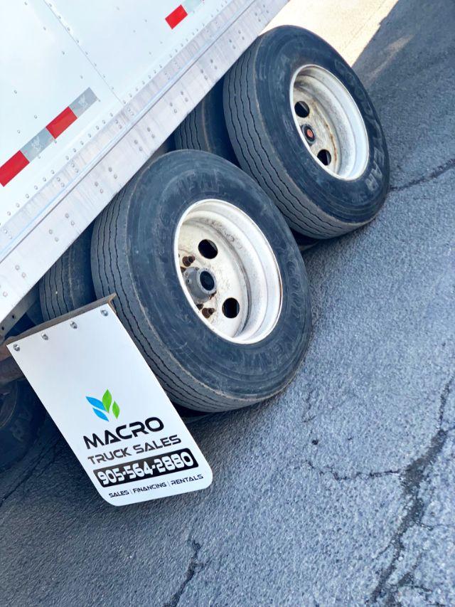Manac dry van trailer axles with dual wheels and a sign reading MACRO TRUCK SALES 905-564-2880.