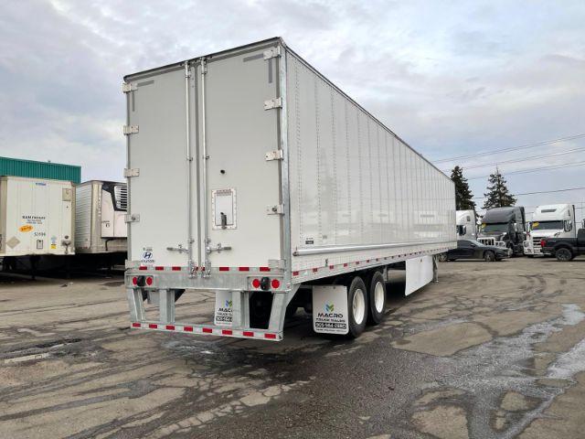 2021 Hyundai dry van trailer side and rear showing reflective tape, three axles with two tires each, rear doors with hinges, MACRO trailer logo on mudflap, and license plate area.