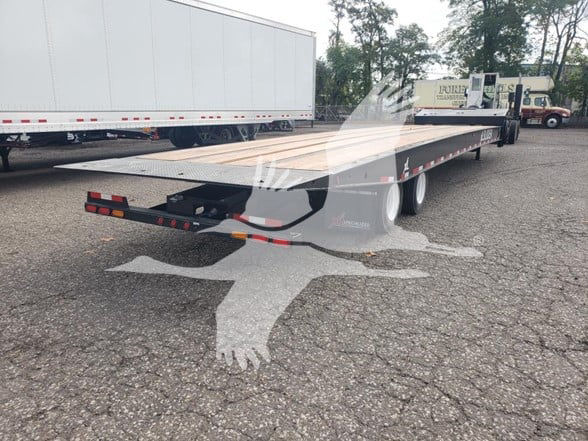 XL Specialized XL80SA trailer flatbed with dual rear axles and ramps visible; side view shows long deck and signage; light traffic in background.