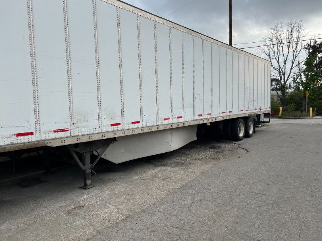 2015 Wabash 53' dry van trailer side view showing tandem axles and landing gear, white exterior with red reflective tape.
