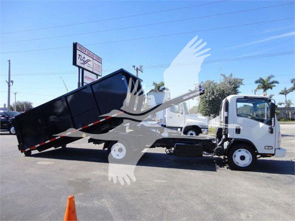 Isuzu NRR truck with tipped dump bed in a dealership lot, cargo area raised at an angle.