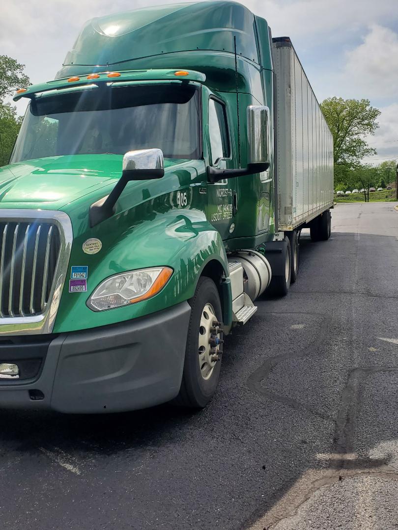 Green 2019 International LT conventional sleeper truck in a parking lot, front-left view with large chrome grille and attached trailer.