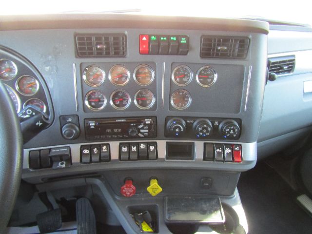 Dashboard of a Kenworth truck showing multiple gauges, switches, and controls in a cab interior.