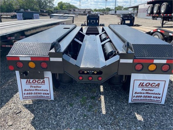 Front view of a 2023 Fontaine 55-ton steel lowboy trailer with a 26ft deck, dual toolboxes, and rear fenders showing LOCA trailer ads.