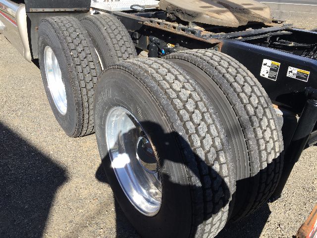 Peterbilt truck rear dual rear axles with dual tires and chrome rim wheels in view.