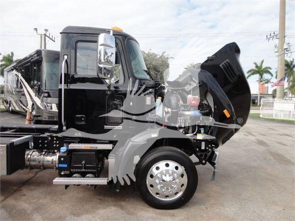 2023 Mack MD6 front-left side showing engine bay and hood open, black cab with chrome mirrors, large front wheel, side steps, equipment components visible.