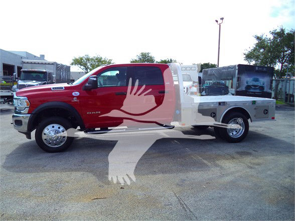 Red Ram 5500 SLT heavy-duty pickup with flatbed, side step, chrome wheels, and service body. Visible text: RAM 5500 emblem on front fender, exterior mirrors, and service bed.