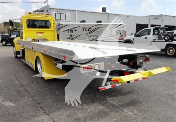 Peterbilt 337 tow truck with a flatbed in a parking lot.