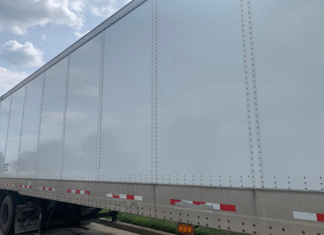 Trailer side panel of a Vanguard VXP utility trailer with riveted aluminum walls and reflective tape along the lower edge.
