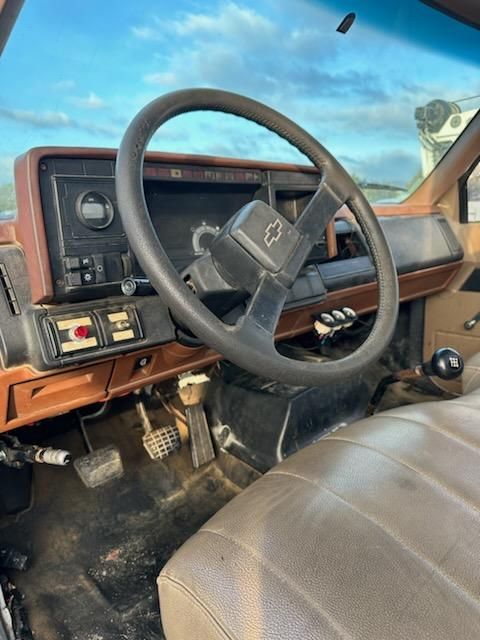 Truck interior showing steering wheel and dashboard in a 1991 Chevrolet Kodiak, manual gear shifter, and brown vinyl interior.