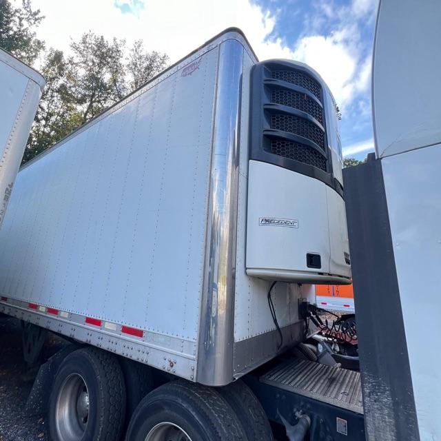 Reefer trailer in service with vertical cooling unit on front corner, aluminum side panels, and dual rear axles visible.