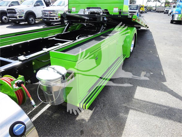Green Peterbilt 337 tow truck chassis with chrome tool reservoir and hydraulic components visible on the side.