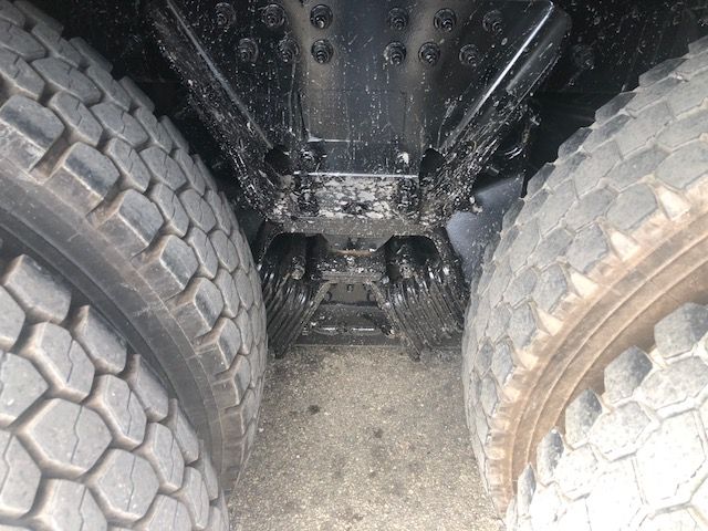 Peterbilt 388 rear undercarriage with dual rear axles, heavy-duty drivetrain, and soil/dirt buildup on tires.