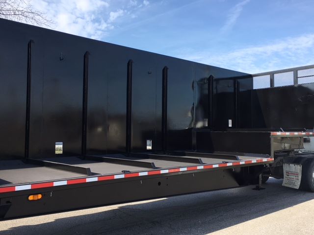Black Great Dane single drop trailer side view showing flatbed with reflective safety stripes and tandem wheels at rear.