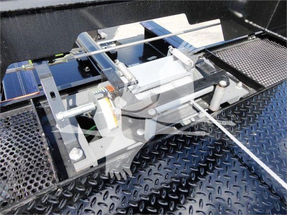 Various metallic components and a mechanical assembly on a diamond plate floor, with rails and brackets.