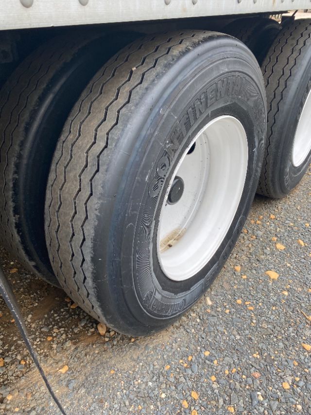 Dual rear wheels on a trailer with Goodyear or similar tires and white rims; visible tread and outer sidewall markings.