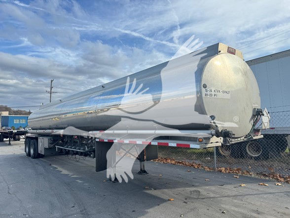 Tank trailer showing polished aluminum Heil 9200 gallon tanker with pump off line and rear with hitch, twin axles, and support legs.