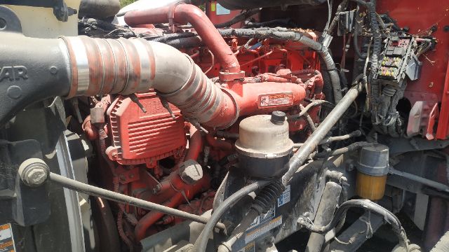 Peterbilt truck engine bay with red engine, various hoses and components visible.