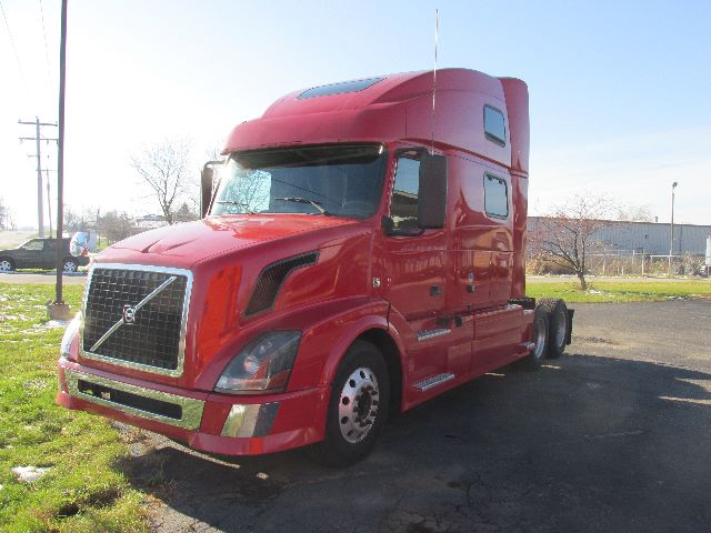Red Volvo 780 conventional sleeper truck shown in an outdoor lot, side view with large aerodynamic cab, Volvo grille emblem on the front.