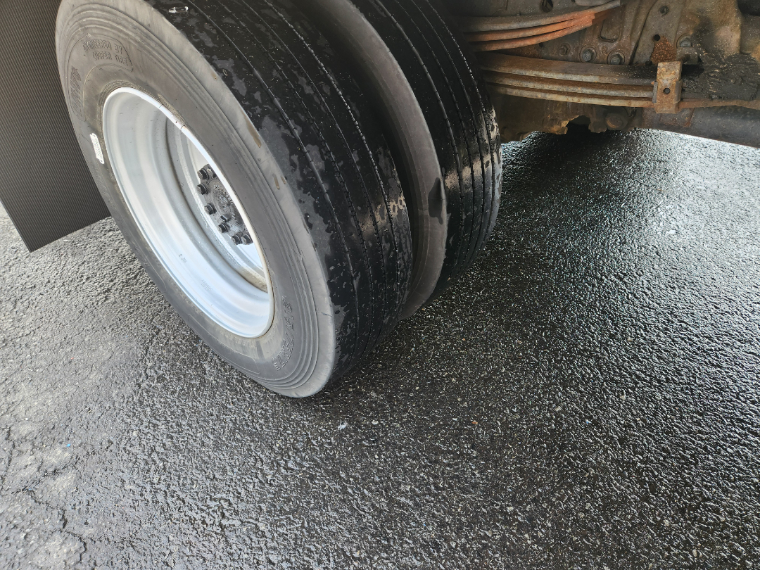 Dual rear axle wheels showing stacked tires on a Hino truck with metal suspension components.
