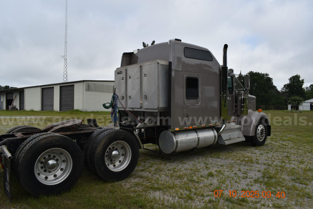 Kenworth W900 cab and chassis tractor with sleeper, side toolbox, and dual rear axles; cylindrical fuel tank under cab; chrome exhaust stack; badge and text on side not legible.