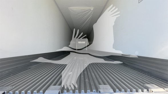Interior of a trailer cargo area with ribbed floor and a large silhouette of a globe and handshake graphic overlaying the image.