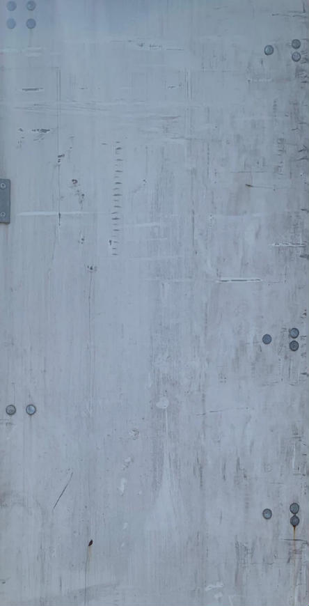 Trailer door surface with light gray paint, multiple circular fasteners, hinges, and a few small scratches.