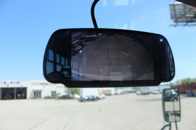 Rearview mirror display showing a reflected parking lot with a building in the background.