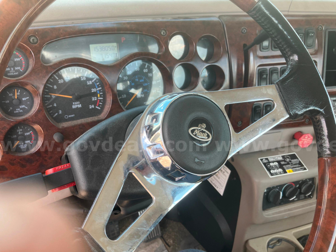 Dashboard and steering wheel of a Mack truck CHN613 showing RPM gauge and cluster with woodgrain dashboard.
