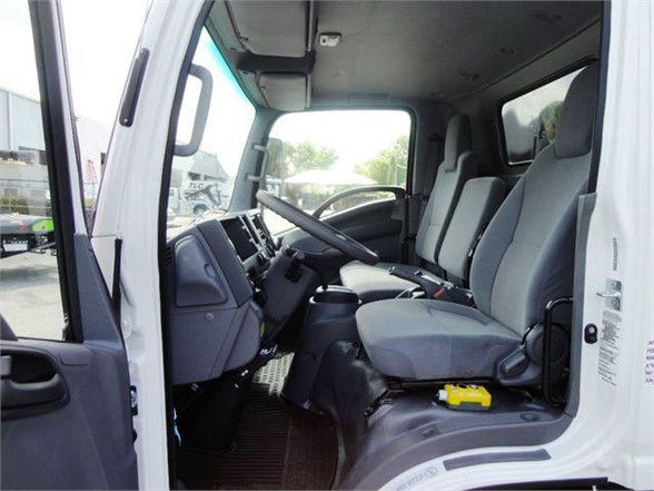 Isuzu NPR HD truck interior showing driver and front passenger seats, steering wheel, dashboard, and center console.