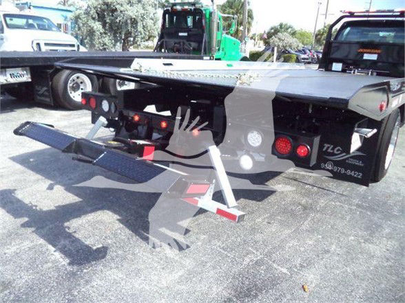 Ford F750 XLT truck bed with dual ramps and TLC branding visible, rear view showing tail lights and hitch area.