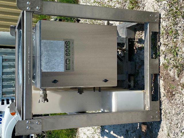 Industrial vapor blasting unit labeled 'EQ 600S' mounted in a metal frame with electrical cabinet and white reservoir on left.