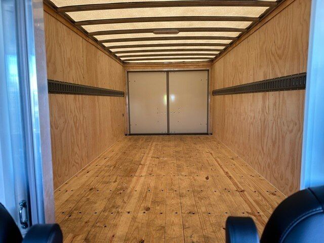 Interior of a cargo box showing plywood walls and floor with a rear double metal door.