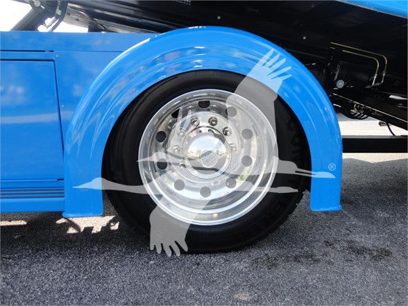 Blue Peterbilt 337 front wheel well and chrome wheel with black tire, portion of blue fender and undercarriage visible.