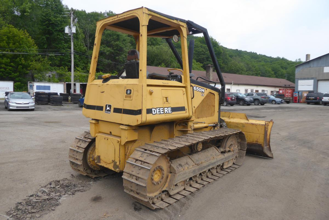 John Deere 650HL Track Loader with blade, side view showing yellow hydraulic tracks and operator cab.