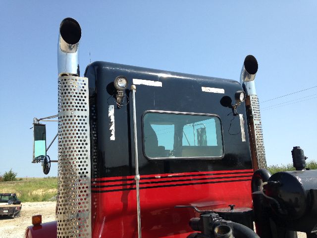 Truck cab rear view of a 2009 Kenworth T800 with black and red paint, dual chrome exhaust stacks, and a small rear window.