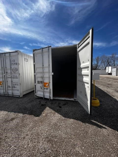 53ft CIMC intermodal dry container with rear and side doors open, empty interior, set on gravel lot with blue sky.