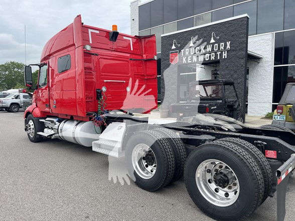 Volvo VNL64T740 truck cab and dual rear axles in a truck lot, red sleeper cab with chrome fuel tanks and fifth wheel