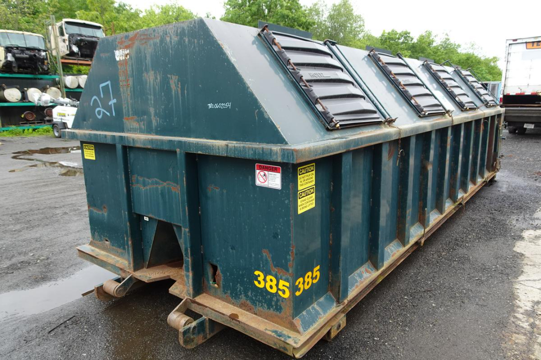 Wastequip 20 yard roll-off dumpster with top access doors and yellow safety labels, side numbers 385 385, on a trailer in a storage lot.