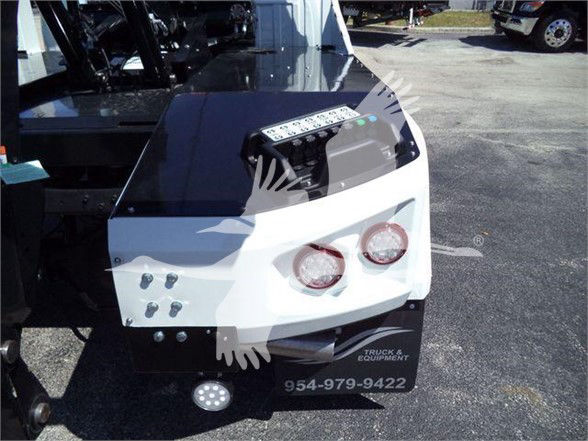Tow truck equipment front bumper with dual round headlights and control panel; visible text includes a phone number 954-979-9422 and a small logo that reads TRUCK & EQUIPMENT near the bottom.