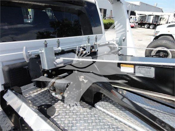 Truck bed with towing equipment, metal Diamond plate floor, and hydraulic/hook system; visible label on side with WARN/Jeep-like sticker.
