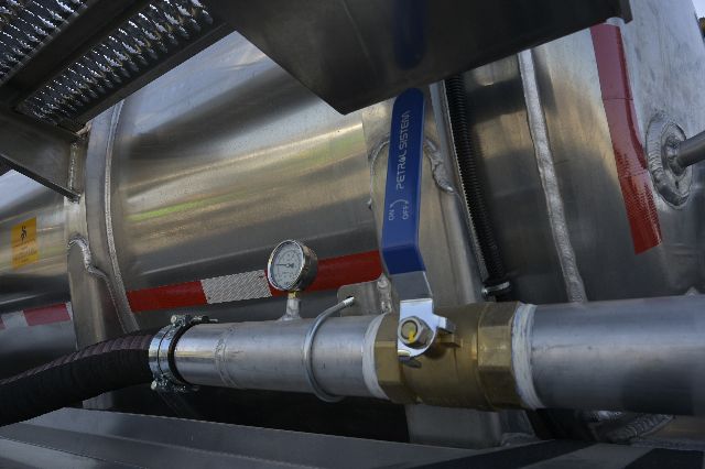 Aluminum vacuum trailer component with a blue TECTRA SYSTEMS valve, pressure gauge, and brass fitting on a stainless pipe. Visible text includes TECTRA SYSTEMS on the blue handle.