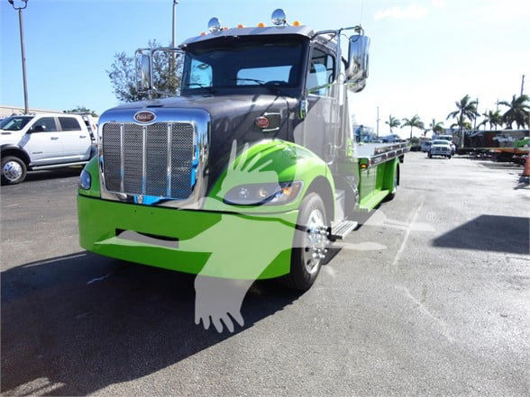 Peterbilt 337 tow truck in green and gray livery with chrome grille and dual mirrors.