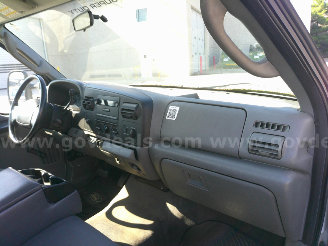 Truck interior showing steering wheel, dashboard with center console, air vents, and glove compartment in a Ford truck cab.